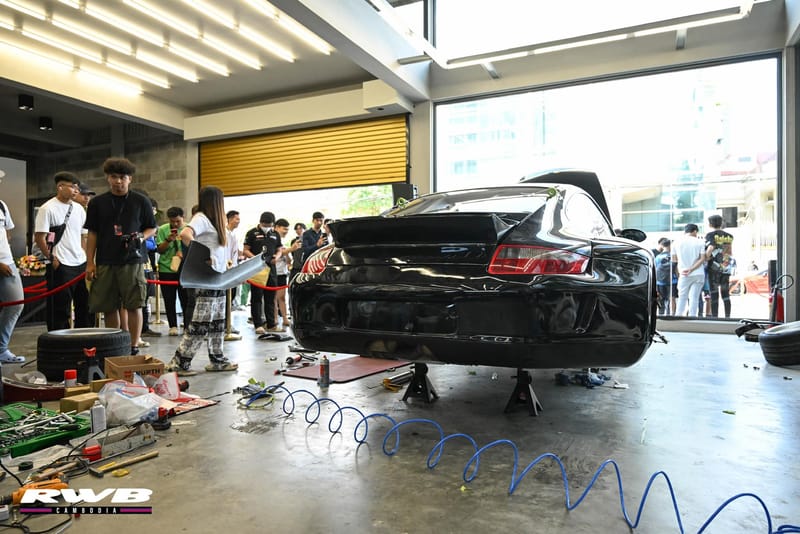 Car on jack stands, crowd watching